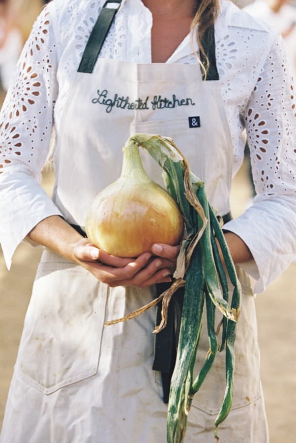A Lighthearted Kitchen chef in an embroidered apron holding just-harvested produce
