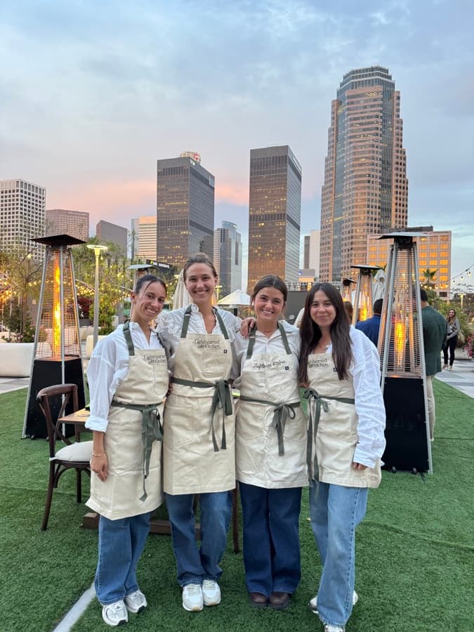 Four Lighthearted Kitchen chefs in embroidered aprons at a rooftop event