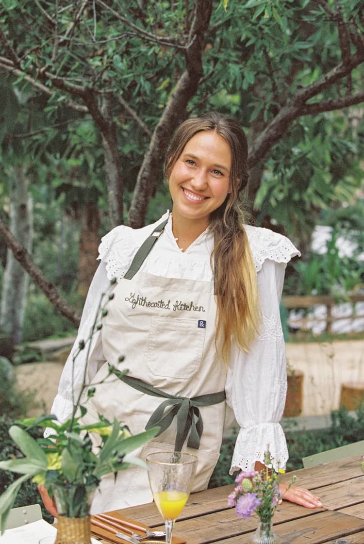 Chelsey Harlien in her Lighthearted Kitchen apron at a set table