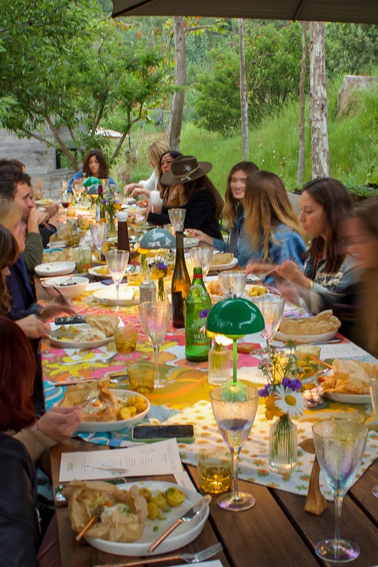 Long, candlelit table set in a private home, guests gathered